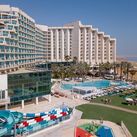 Leonardo Club Hotel Dead Sea Neve Zohar Extérieur photo The image shows a large hotel complex alongside a pool area. The hotel features modern architecture with multiple levels and numerous balconies. In front of the hotel, there is a recreational area with a swimming pool, water slides, and lounging chai
